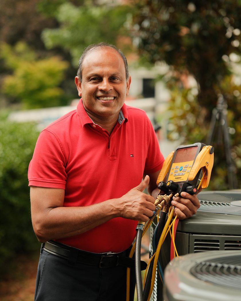The owner checking refrigerant pressures with digital gauges on a finished outdoor unit.